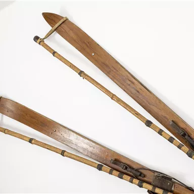 Two old wooden swings hang on the wall. They have a rustic look and are connected with ropes and trees.