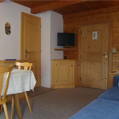 Ein gemütlicher Wohnbereich mit Holzverkleidung und einem kleinen Essbereich. Eine Fernsehecke und Dekorationen runden das Ambiente ab.