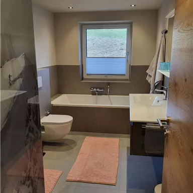 A modern bathroom with a bathtub and a shower. The room is bright and cheerful with a large window.