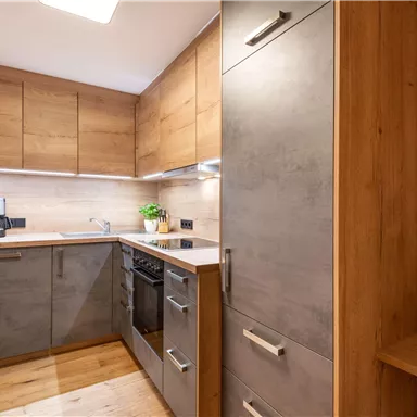 A modern kitchen with wood and concrete elements. The appliances are functional and the space feels inviting.