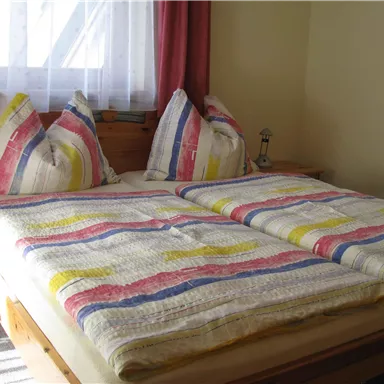A cozy bedroom with a large double bed and colorful bedcovers.
Soft pillows and warm light create an inviting atmosphere.