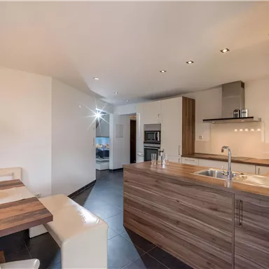 A modern kitchen with wooden details and a dining area. The room is brightly and cheerfully designed.