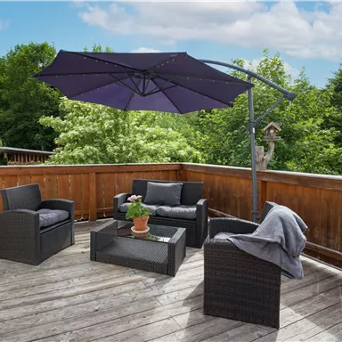 A cozy terrace corner with a sun umbrella and stylish furniture. Surrounded by green foliage and a wooden railing.