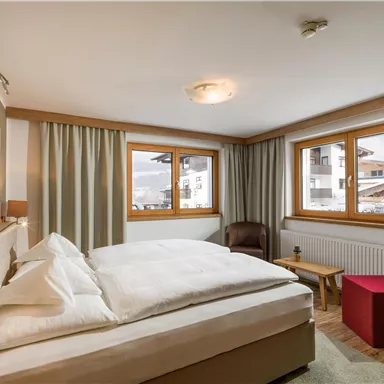 Ein gemütliches Schlafzimmer mit einem großen Bett und mehreren Fenstern. Die Einrichtung ist modern und ansprechend.