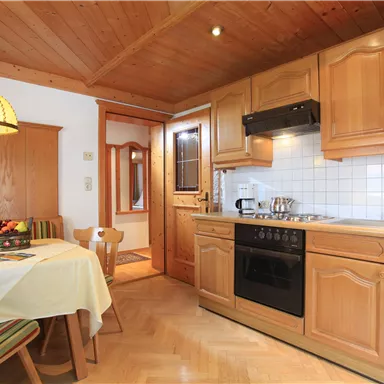 A cozy kitchen with wooden cabinets and a dining table. The decor is bright and inviting, with a typical alpine flair.