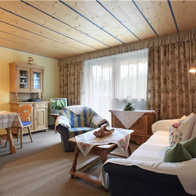 A cozy living room with a white sofa and a wooden table.
Large windows let in plenty of light, and the walls are decorated in bright colors.