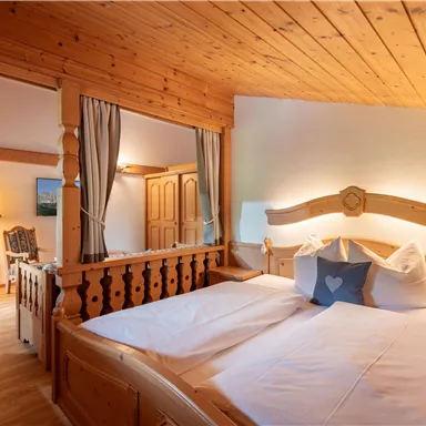 Ein gemütliches Schlafzimmer mit einem Holzinterieur. Es gibt zwei Betten, eine warme Atmosphäre und ein Fenster, das viel Licht hereinlässt.
