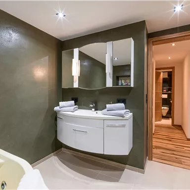 Ein modernes Badezimmer mit einem eleganten Waschbecken und Spiegel. Der Raum hat eine warme Farbgestaltung und verfügt über sanfte Beleuchtung.