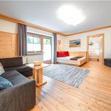 Ein gemütliches Wohnzimmer mit Holzmöbeln und einem großen Fenster. Die Einrichtung ist modern und einladend, ideal für entspannte Momente.