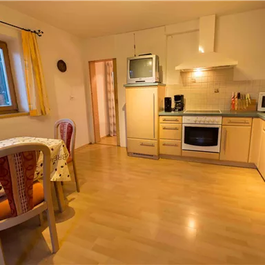 A modern kitchen with wooden cabinets and a dining set. The light is warm and the atmosphere feels cozy.
