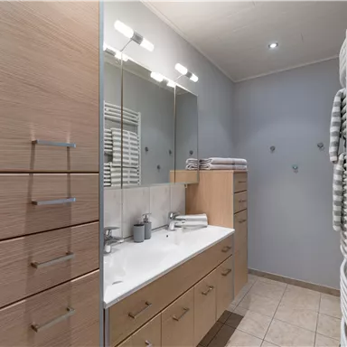 A modern bathroom with wooden cabinets, a large mirror, and a bright tiled surface. The kitchen is well-organized and provides ample storage space.