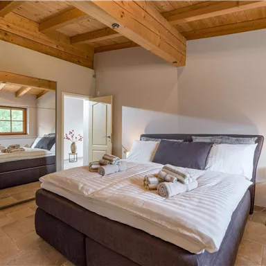 A cozy bedroom with a large double bed and modern furniture.  
On the wall, there is a mirror, and the atmosphere is bright and inviting.