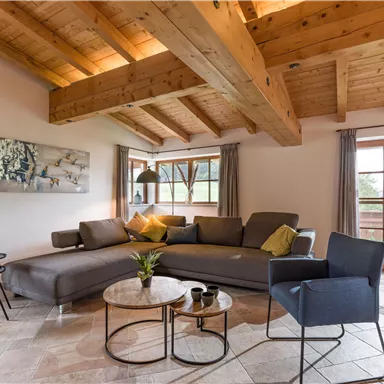 A modern living room with a cozy couch and a small table. Large windows let in plenty of natural light.