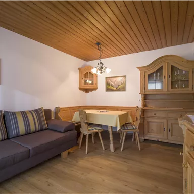 A cozy living space with a gray sofa and a dining area. Wooden paneling and furniture give the room a warm atmosphere.