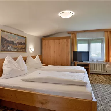 Ein gemütliches Hotelzimmer mit zwei Betten und Holzmöbeln. Das Zimmer hat ein Fenster mit viel Tageslicht und eine Fernsehecke.