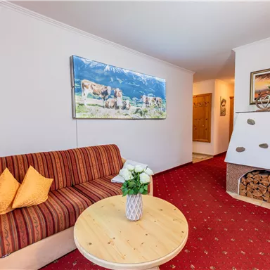 Ein gemütliches Wohnzimmer mit einem gestreiften Sofa und einem runden Tisch. An der Wand hängt ein Landschaftsgemälde, und neben dem Sofa steht ein dekorativer Kamin.