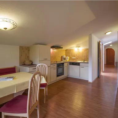 A bright and modern kitchen with a dining table and chairs. The room has wooden floors and a cozy atmosphere.