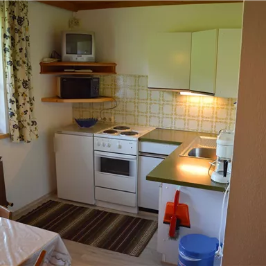 A modern kitchen with white cabinets and a green countertop. The kitchen is bright and inviting, equipped with basic appliances.