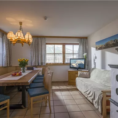 Ein gemütlicher Essbereich mit einem großen Tisch und Stühlen. Das Zimmer ist hell beleuchtet und hat ein Fenster mit Blick nach außen.