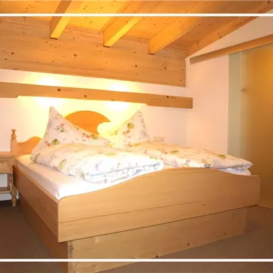 A cozy bedroom with a large bed and wooden ceiling. The room has a bright atmosphere and access to the bathroom.