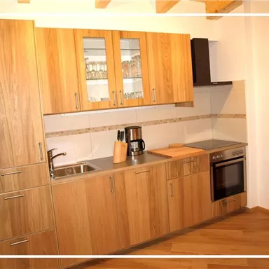A modern kitchen with wooden cabinets and stainless steel appliances. The countertop is bright and clearly designed.