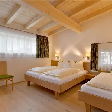 Ein gemütliches Schlafzimmer mit zwei Einzelbetten und hellen Holzmöbeln. Die großen Fenster sorgen für viel Tageslicht.