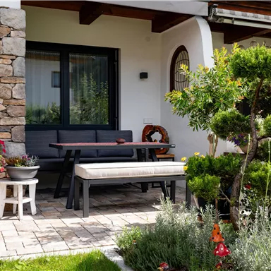 An inviting outdoor area with comfortable furniture and colorful flowers. In the background, the stone walls and a well-maintained garden are visible.