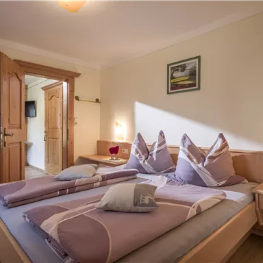 Ein gemütliches Schlafzimmer mit zwei Betten und einem warmen Farbton. Die Einrichtung ist schlicht und einladend, mit natürlichem Licht, das den Raum erhellt.