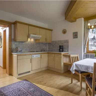 A bright kitchen with modern wooden design and a dining table. There is a beautiful bouquet of flowers on the table and a cozy atmosphere.