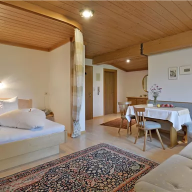 Ein gemütliches Zimmer mit einem Doppelbett, einer Sitzecke und einem Essbereich. Der Raum hat ein warmes, einladendes Ambiente.