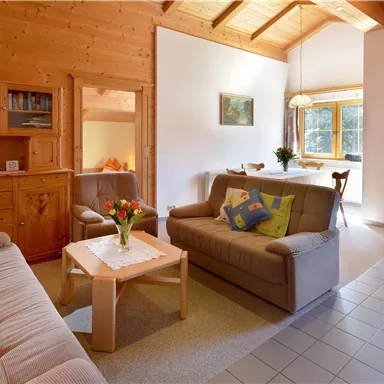 A cozy living room with wooden walls and a high ceiling. Two sofas and a table create an inviting atmosphere.