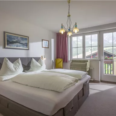 Ein modernes Schlafzimmer mit zwei Betten und großen Fenstern. Die Wände sind hell gestrichen, und es gibt einen schönen Blick auf die Berge.