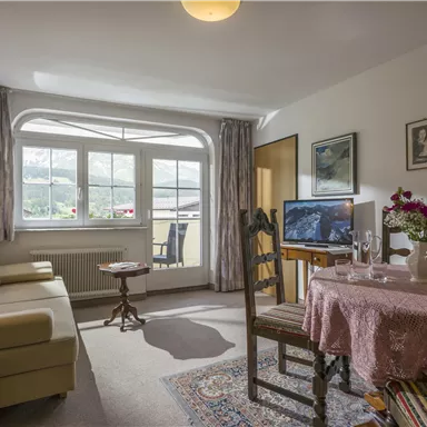 Eine gemütliche Wohnung mit einem hellen Wohnzimmer. Der Raum ist mit einem Sofa, einem Tisch und einem Fernseher ausgestattet.