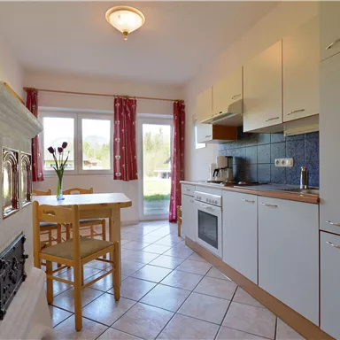A bright kitchen with modern cabinets and appliances. A table with chairs is next to a window that lets in light.