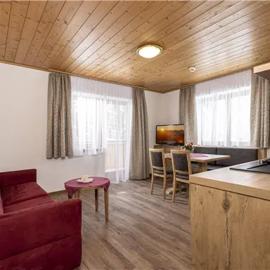 A cozy living kitchen with a sofa and a table.  
Large windows let in plenty of light and create an inviting atmosphere.