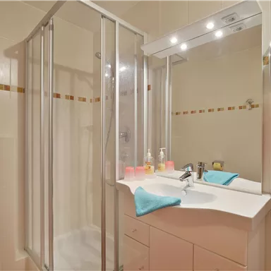 A modern bathroom with a shower cabin and a sink. The walls are light, and there are colorful towels for a fresh accent.