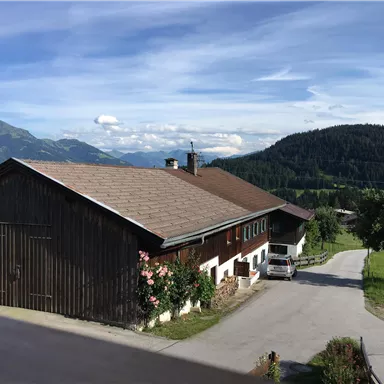Ein traditionelles Haus im ländlichen Gebiet mit einer schönen Landschaft im Hintergrund. Die Berge und der klare Himmel verleihen der Szenerie eine friedliche Atmosphäre.