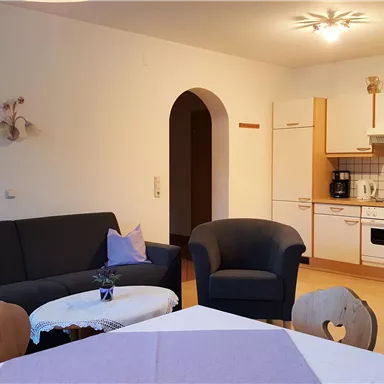 A cozy apartment with a living room and an open kitchen. The decor is modern and inviting, perfect for a relaxing stay.