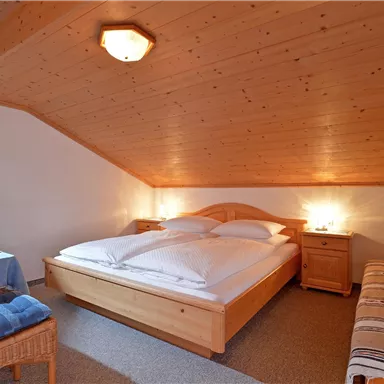 Ein gemütliches Schlafzimmer mit einem Doppelbett und einem Sitzbereich. Der Holzdekor verleiht eine warme Atmosphäre.