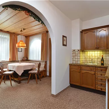 A cozy kitchen with wooden cabinets and a dining area. The room is bright and friendly designed.