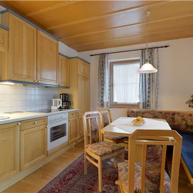 A bright kitchen with wooden cabinets and a dining table. The decor is cozy and inviting.