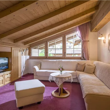 A cozy living space in the attic with a bright seating area. Large windows provide plenty of daylight and a warm atmosphere.