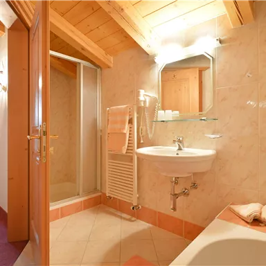 A modern bathroom with a shower and sink. Bright tiles and wooden details create an inviting atmosphere.