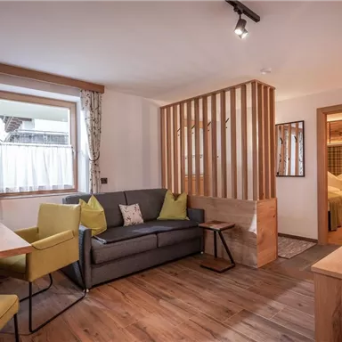 Ein gemütlicher Wohnbereich mit einer Sitzgruppe und einem Esstisch. Gutes Licht und Holzdetails schaffen eine einladende Atmosphäre.