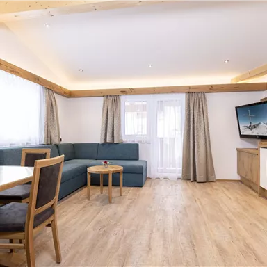 A modern living room with a cozy sofa and a wooden table. Large windows provide plenty of daylight and a welcoming atmosphere.