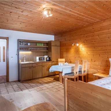 Ein gemütliches Zimmer mit Holzverkleidung und einem Schlafzimmer. Die kleine Küche ist gut ausgestattet und es gibt einen Essbereich.