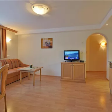 A cozy apartment with a living room, a couch, and a television. The room has bright colors and plenty of natural light.