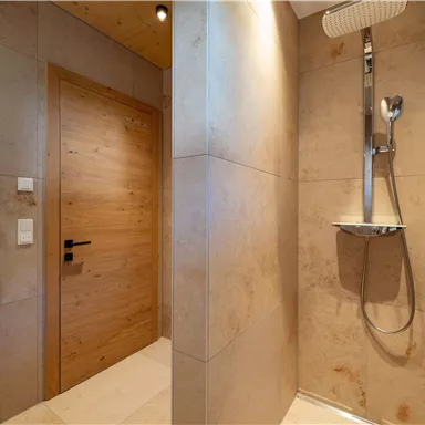 A modern bathroom with a shower and a wooden sliding door. The walls are in neutral colors and convey an elegant ambiance.