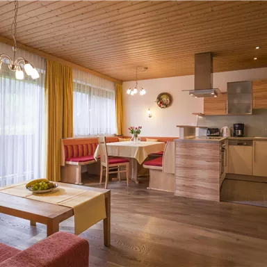A modern living-dining room with an open kitchen. Bright colors and large windows create a friendly atmosphere.