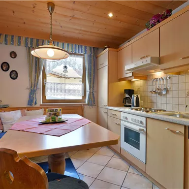 A cozy kitchen with wood paneling and modern amenities. The dining table is beautifully set and invites you to linger.